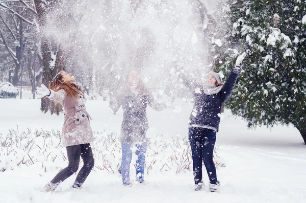 Three teenage girls throwing snow in the air on beautiful winter