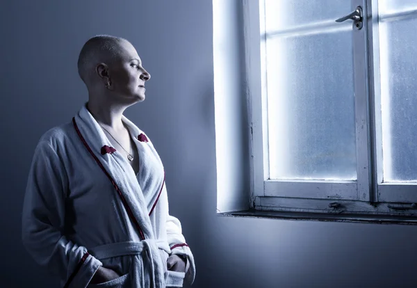 Bald woman suffering from cancer looking throught the hospital w