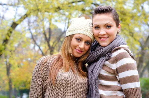 Two beautiful girlfriends having fun in the park on colorful autumn day