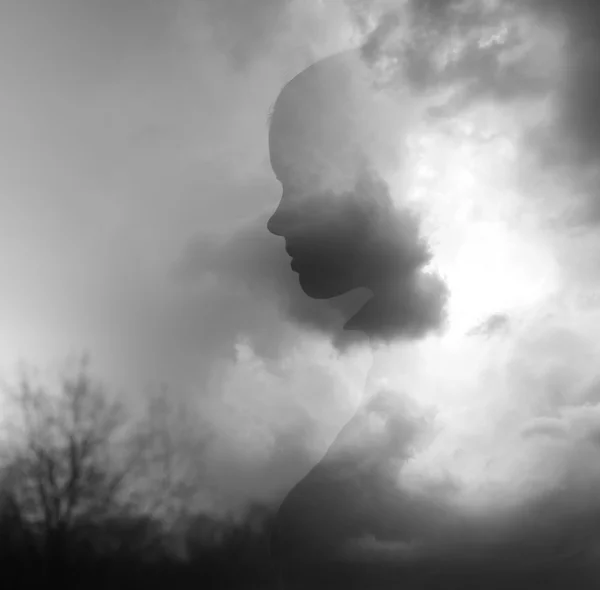 Double exposure image made of silhouette of young girl emerging from  clouds