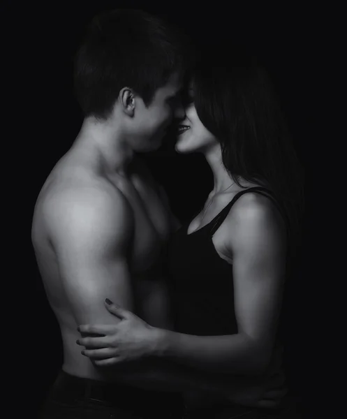 Beautiful young couple hugging and kissing isolated on black background