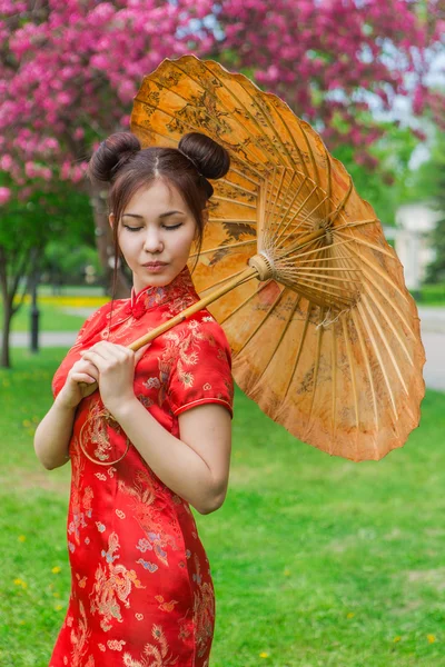 Beautiful asian girl in traditional chinese red dress with bamboo umbrella.