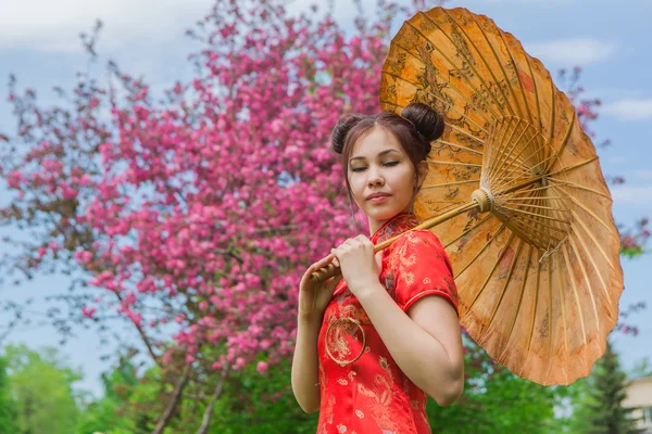 Beautiful asian girl in traditional chinese red dress with bamboo umbrella.