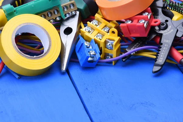Tools and component kit used in electrical installations on blue background