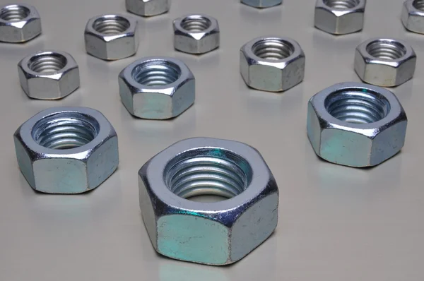 Group of steel nuts with green light reflection