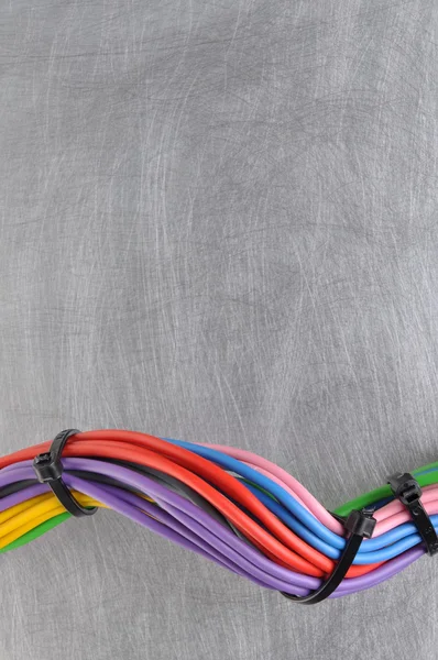Multicolored electric cables on gray metal surface with place for text