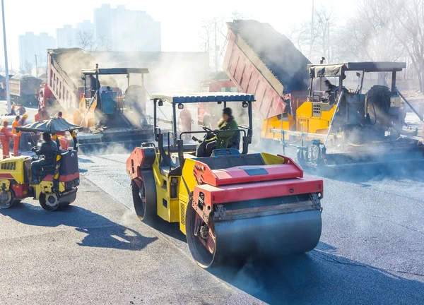 Workers making asphalt with shovels at road constructio