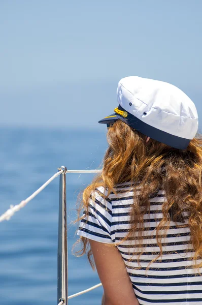 Young marine style woman is sitting on the boat and looking forward