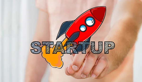 Businessman touching hand drawn startup text and red rocket