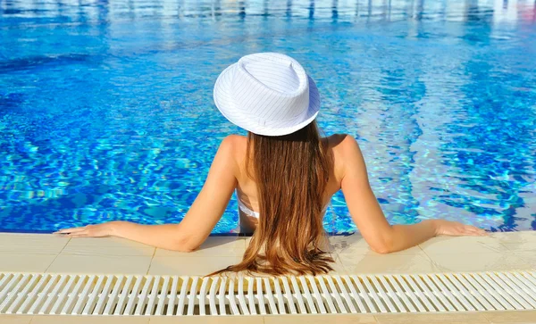 Beautiful woman white hat and bikini in a pool