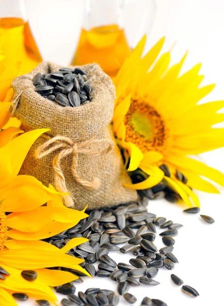 Small bag with sunflower seeds on a background of flowers and a bottle of sunflower oil