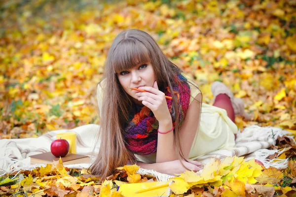 Beautiful girl with notebook on a background autumn leaves