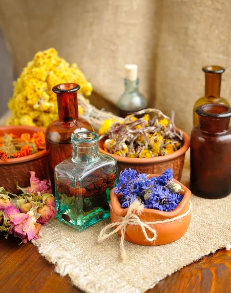 Healing herbs and tinctures in bottles on sackcloth, dried flowers, herbal medicine
