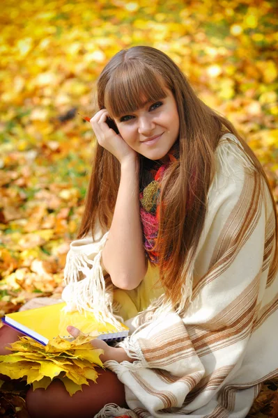 Beautiful girl with notebook on a background autumn leaves