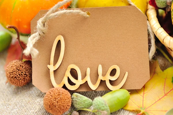 Word LOVE on the background of the label with autumn leaves and