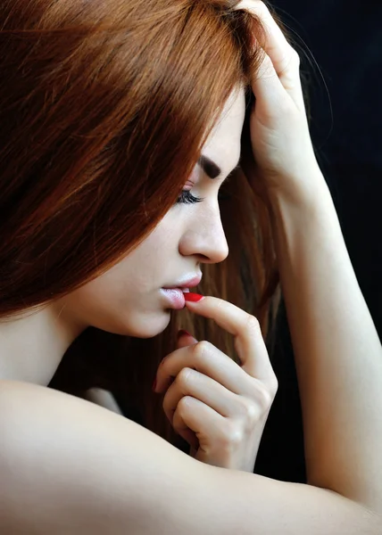 Profile of young pensive woman with red hairs on black backgroun
