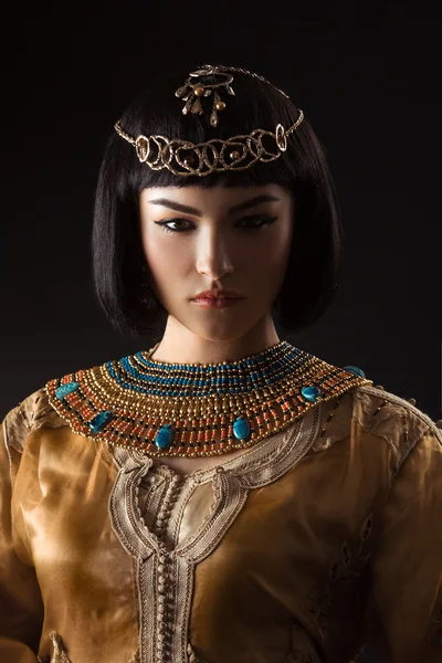 Beautiful woman like Egyptian Queen Cleopatra with serius face on black background