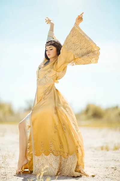 Beautiful woman like Egyptian Queen Cleopatra on in desert outdoor.