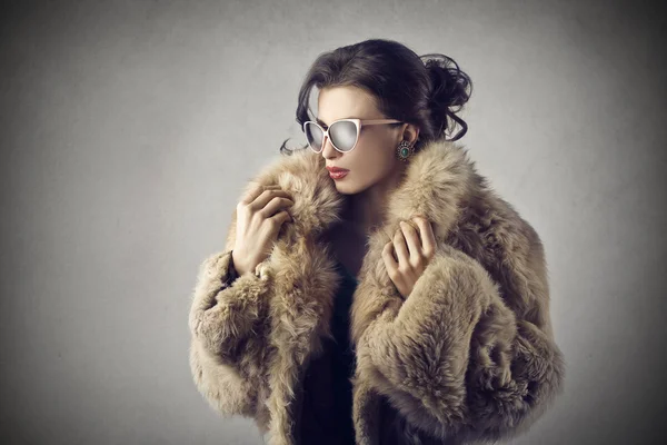 Elegant girl wearing sunglasses and a fur coat