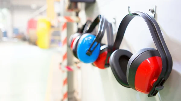 Row of Ear Defenders hung up in a factory with copy space