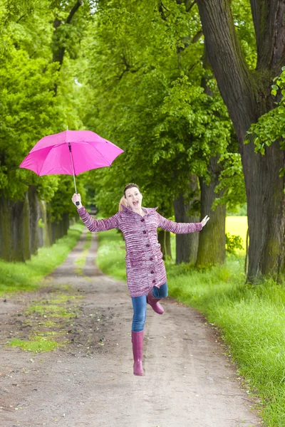 Woman wearing rubber boots with umbrella in spring nature