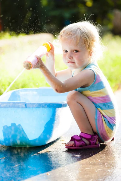 Toddler girl playing with water sprayer
