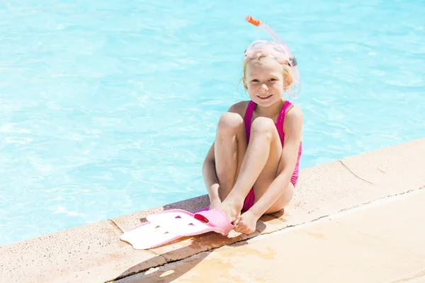 Little girl with snorkeling equipment at swimming pool