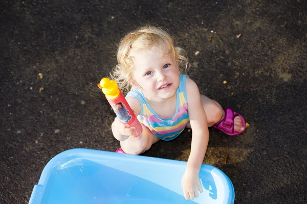 Toddler girl playing with water sprayer in summer