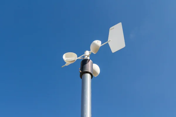 Close up of the anemometer on top of the pole against the clear blue sky.