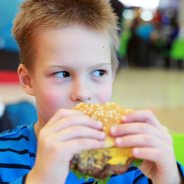 Little boy eating burger