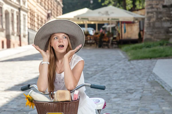 Surprised women on pink bicycle with grocery basket