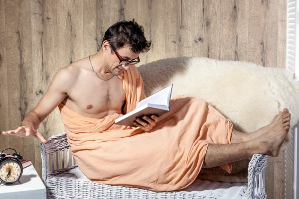 Man reading on couch when alarm clock rings
