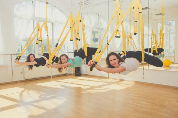 Group of women doing yoga in hammocks
