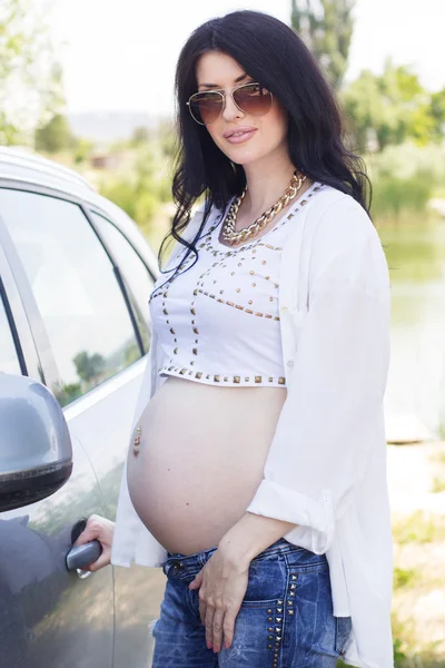 Pregnant pretty girl is standing near car