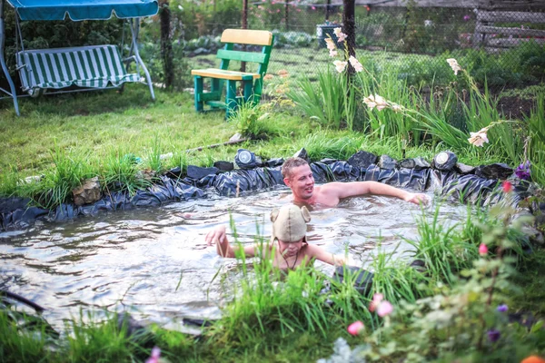 In the summer, bright sunny day, happy family is bathed dives, into the pond. Water splashes