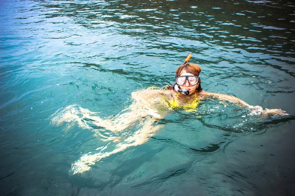 Young woman snorkeling in blue and transparent tropical sea