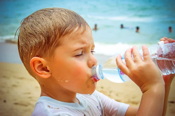 小男孩喝水后刻苦的游泳的海滩上 - 图库照片e