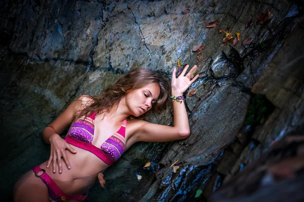 Beautiful sexy model posing in water of waterfalls wearing bikini swimwear at summer time