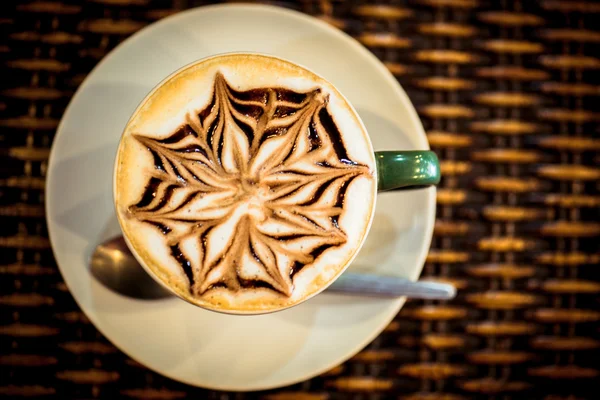 Cup of coffee latte with design art in froth, on a wooden table. Close up macro