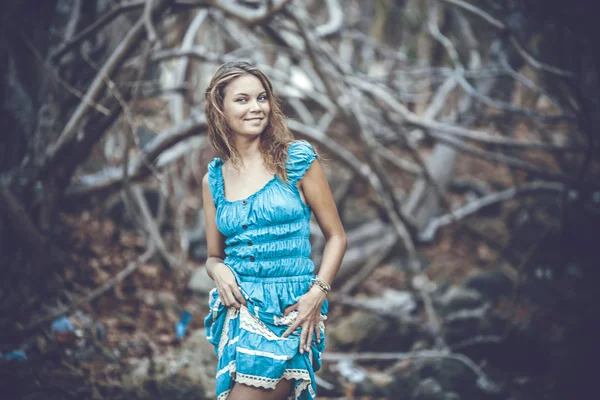 Portrait of a beautiful young smiles woman in turquoise dress standing by trees In jungle forest