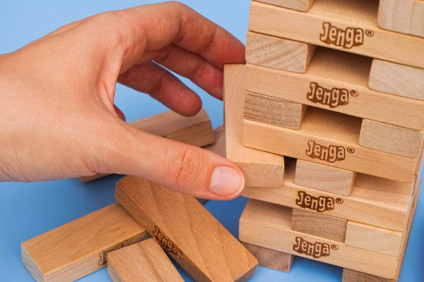 Human hand removing one block from Jenga tower