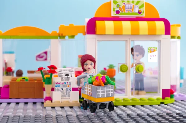 Lego girl with trolley of food came out from supermarket.