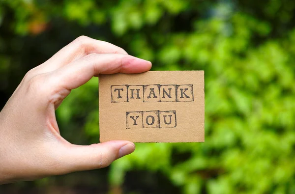 Woman hand holding cardboard card with words Thank You