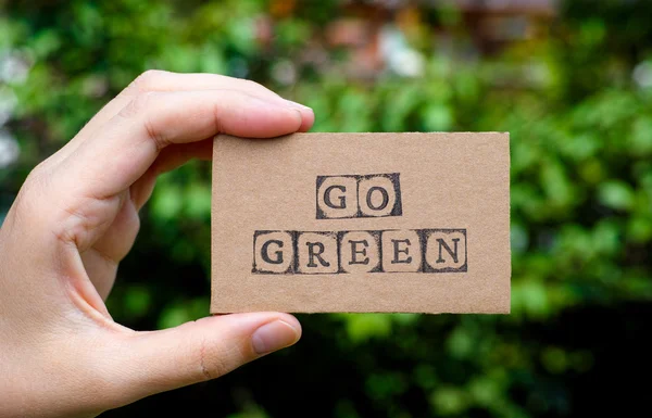 Woman hand holding cardboard card with words Go Green