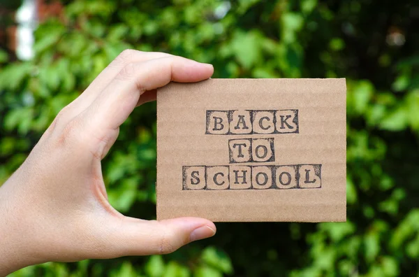 Woman hand holding cardboard card with words Back to School