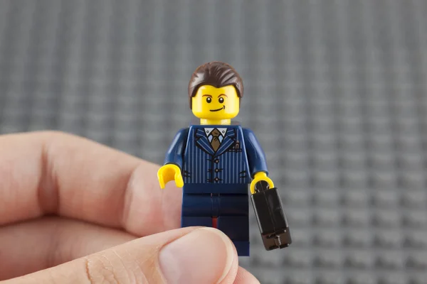 Lego businessman in human hand