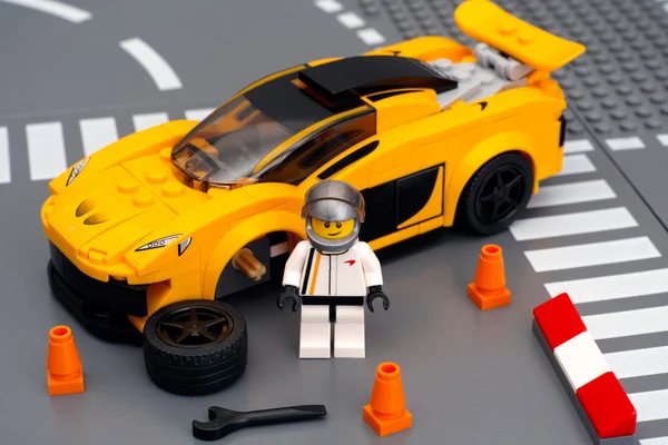 Lego driver minifigure near his car McLaren P1 with broken wheel