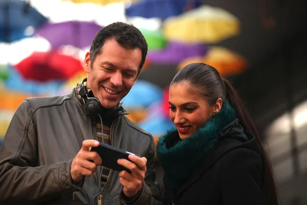 Cheerful man and woman friends looking at mobile smart phone, some photo grain