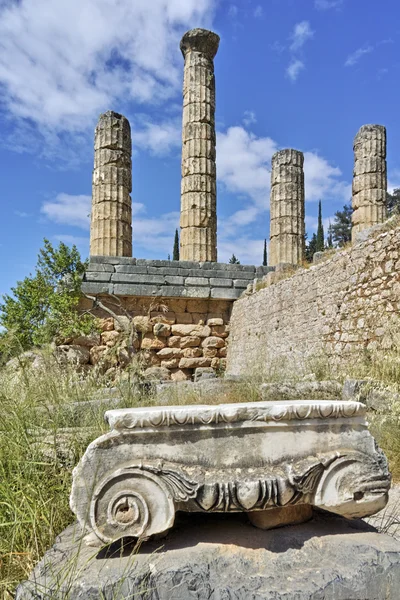 Ancient column and The Temple of Apollo in Ancient Greek archaeological site of Delphi