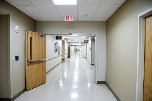 Well lit hospital corridor with heavy oak doors